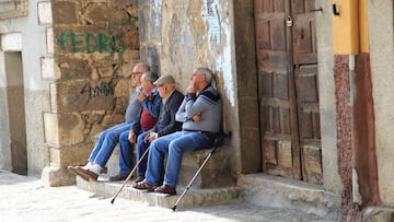 Men sitting together on stone bench, Garganta la Olla, La Vera, Extremadura, Spain. (Photo by: Geography Photos/Universal Images Group via Getty Images)