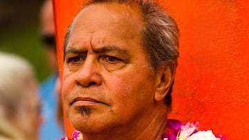 Clyde Aikau con un collar de flores ante su tabla de surf roja durante una participación en el Eddie Aikau, campeonato de surf de olas grandes de Waimea Bay, en 2019