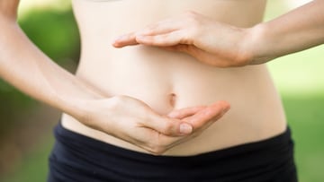 Close-up of hands of young Caucasian woman showing her slim belly. Fitness and dieting concept