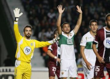 El delantero del Elche Cristian Herrera (c) y el portero del Córdoba Juan Carlos Martín (i), esperan un saque de esquina durante el partido de la duodécima jornada de liga de Primera División disputado esta tarde en el estadio Martínez Valero.