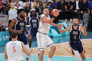 Serbia's #15 Nikola Jokic (C) challenges USA's #04 Stephen Curry (R) in the men's preliminary round group C basketball match between Serbia and USA during the Paris 2024 Olympic Games at the Pierre-Mauroy stadium in Villeneuve-d'Ascq, northern France, on July 28, 2024.