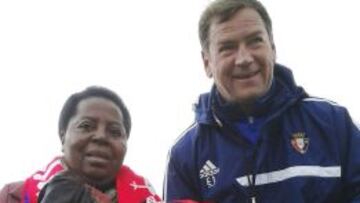 La misionera Juliana Bonoha, que estuvo 21 días ingresada y aislada por haber estado en contacto con el virus del ébola, recibe de manos del entrenador polaco de Osasuna, Jan Urban, una camieta firmada por la plantilla "rojilla", durante la visita que la religiosa realizó en Tajonar para presenciar el entrenamiento de Osasuna, equipo del que es "gran aficionada", antes de partir hacia Guinea, su país natal.