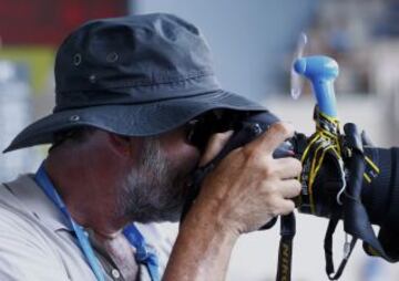 Un fotógrafo se mantiene fresco con un ventilador pegado a su cámara durante el torneo de tenis de Australia