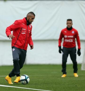 Arturo Vidal controla el balón y de fondo lo observa Alexis Sánchez. 