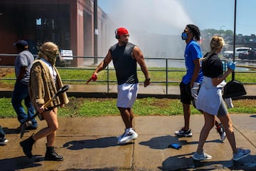 People walk with tools on their way to help clean up the street following a day of demonstration in a call for justice for George Floyd, who died while in custody of the Minneapolis police, on May 30, 2020 in Minneapolis, Minnesota. - Demonstrations are being held across the US after George Floyd died in police custody on May 25. (Photo by Kerem Yucel / AFP)