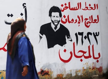 An Egyptian woman walks in front of picture depicting Liverpool's Egyptian forward Mohamed Salah