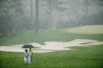 Rory McIlroy y su caddie aguantan bajo el paraguas la impresionante cortina de agua que cayó durante la sesión de preparación para el Torneo de Augusta.