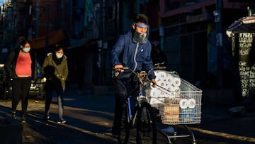 A worker wearing a face mask as a preventive measure against the novel coronavirus, COVID-19, rides a bicycle while pulling a trolley along a street in Villa 31 shantytown in downtown Buenos Aires, on May 5, 2020. - Villa 31, the oldest shantytown in Buenos Aires, is separated only by an avenue from exclusive neighbourhoods of the capital. Crowded, hungry and suffering water services faults, residents of the slum now face the menace of COVID-19. (Photo by Ronaldo SCHEMIDT / AFP)