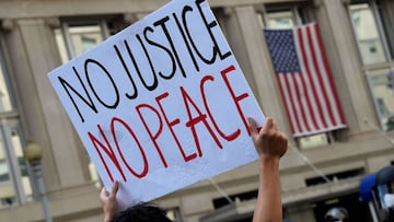 Demonstrators protesting the death of George Floyd hold up placards as they face a police line near Lafayette park accross the White House on June 2, 2020 in Washington, DC. - Anti-racism protests have put several US cities under curfew to suppress riotin