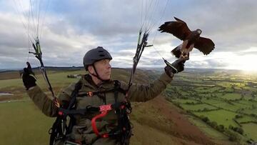 El parapentista Nigel Hawkins practicando parapente sobre Inglaterra mientras con una mano sujeta a su halcón Frederick.