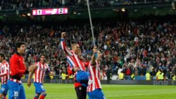 Jugadores atléticos hacen ondear una bandera en el Bernabéu tras el triunfo en la final de Copa.
