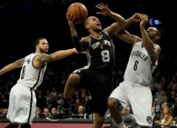 Patty Mills trata de lanzar entre Alan Anderson y Deron Williams durante el Brooklyn-San Antonio.