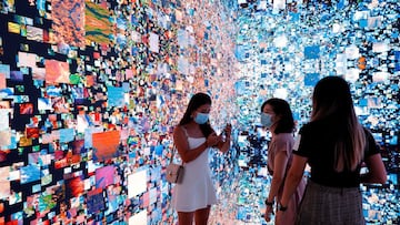 Visitors are pictured in front of an immersive art installation titled "Machine Hallucinations — Space: Metaverse" by media artist Refik Anadol, which was auctioned as an NFT in September.