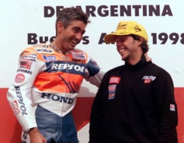 Octubre de 1998. Un Mick Doohan campeón del Mundo de 500cc por quinta vez consecutiva felicita al nuevo campeón de 250, Loris Capirossi.