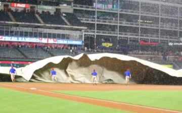 El staff del estadio de los Texas Rangers no pudo tapar el campo de béisbol por el viento y la lluvia.