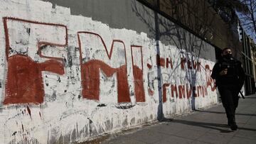 (FILES) In this file photo taken on August 03, 2020 a policewoman walks past a wall with a reading &quot;IMF, the Worst Pandemic&quot; in Buenos Aires, amid the COVID-19 novel coronavirus pandemic. - Argentina payed on August 2, 2021, 334 million dollars of interests for the stand-by credit agreed in 2018 with the International Monetary Fund (IMF), from which the country received some 44,000 million dollars, which it is trying to replace for another accord with extended facilities. (Photo by Juan MABROMATA / AFP)