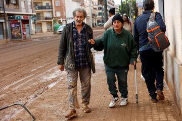 La gente camina por una calle cubierta de barro, tras las fuertes lluvias del pasado 29 de octubre.