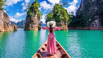 Beautiful girl standing on the boat and looking to mountains in Ratchaprapha Dam at Khao Sok National Park, Surat Thani Province, Thailand.
