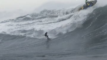 Un surfista meti&eacute;ndose en una ola gigante de la borrasca Denise en Illa Pancha (Ribadeo, Lugo, Galicia, Espa&ntilde;a) el 22 de noviembre del 2022. Por arriba, un Jet Ski escapa de la ola. 