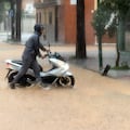 Incidencias en la capital malagueña con motivo de las precipitaciones. Una persona traslada a pie una motocicleta en el barrio de Campanillas, Málaga.