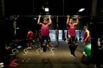 Beauden Barrett (a la izquierda) y Will Jordan hacen dominadas en barra, con unas pesas colgadas de sus respectivas cinturas, durante una sesión de Les Mills en el gimnasio de los All Blacks de rugby. Les Mills es una variedad del fitness, creada en Nueva Zelanda, que ha revolucionado los entrenamiesntos tradicionales en el gimanasio.