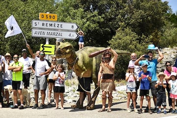 Un espectador disfrazado de hombre prehistórico y otro vestido como un dinosaurio anuncian una visita turística a la cueva de Aven Marzal.