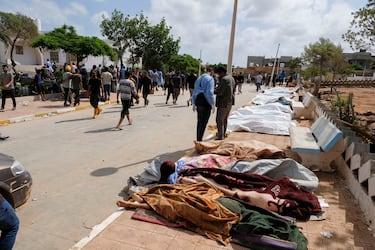 La gente pasa junto a los cadáveres tendidos en el suelo fuera del hospital. 