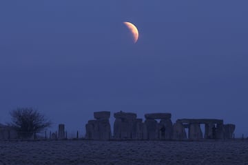 La gente observa la luna llena mientras una secci¨®n se mueve hacia la sombra durante un eclipse lunar, antes del amanecer, en el c¨ªrculo de piedras de Stonehenge, cerca de Amesbury, en el sur de Gran Breta?a