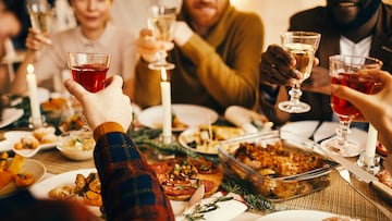 Close up of modern adult people raising glasses while enjoying Christmas dinner at home, copy space