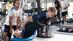 Martin Odegaard realiza un ejercicio en el gimnasio de Valdebebas ayudado por un miembro del cuerpo t&eacute;cnico durante la pretemporada del Real Madrid.