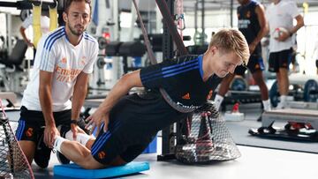 Martin Odegaard realiza un ejercicio en el gimnasio de Valdebebas ayudado por un miembro del cuerpo técnico durante la pretemporada del Real Madrid.