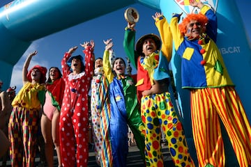 Participantes vestidos de payasos multicolor se preparan para saltar al agua del Puerto Viejo de Barcelona, lugar donde se disputa la tradicional Copa Nadal.