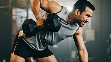 Man, dumbbell and weightlifting in fitness, workout or arm exercise on bench at indoor gym. Serious male person, bodybuilder or athlete lifting weight in sports training, health and wellness at club