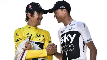(FILES) In this file photo taken on July 29, 2018, Tour de France 2018 winner Great Britain's Geraint Thomas (L), wearing the overall leader's yellow jersey, shakes hands with third-placed Great Britain's Christopher Froome on the podium after the 21st an