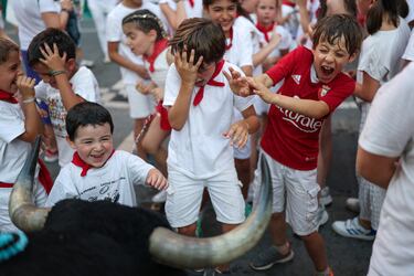 Los niños son rociados con agua y perseguidos por un toro sobre ruedas mientras recorre las calles durante los encierros de San Fermín, en Pamplona (España). 