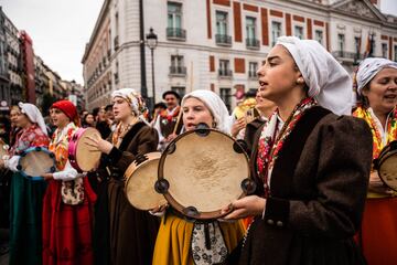 Varias mujeres vestidas con trajes regionales reciben al rebaño trashumante a su paso por la Puerta del Sol.