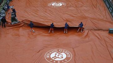 Los operarios de Roland Garros cubren la arcilla de la pista Suzanne Lenglen a causa de la lluvia.