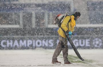 Un operario del club italiano retira la nieve de las lineas del terreno de juego.