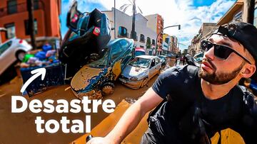 Oriol Inglada con su bici delante de unos coches amontonados y embarrados en Valencia.