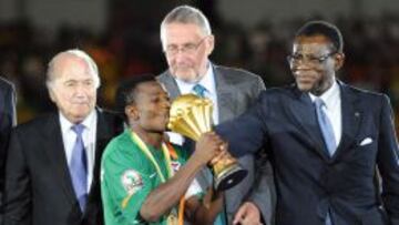 CAMP&Eacute;ON. Katongo, capit&aacute;n de Zambia, recibe la Copa de Africa de 2012 de manos de Obiang.
 
