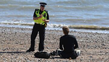 BRIGHTON, ENGLAND  - APRIL 04: A police officer moves a member of the public off Brighton beach on April 04, 2020 in Brighton, England. The Coronavirus (COVID-19) pandemic has spread to many countries across the world, claiming over 50,000 lives and infec