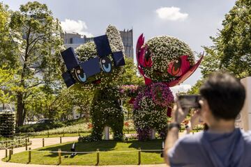 Una pareja de turistas toma fotografías en un parque de Tokio a un seto que representa a las mascotas de los Juegos Olímpicos y Paralímpicos: Miraitowa y Someity. Miraitowa combina las palabras japonesas mirai (futuro) y towa (eternidad). Someity se llama así en honor a una variedad de flor de cerezo conocida como someiyoshino.