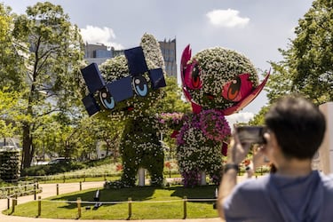 Una pareja de turistas toma fotografías en un parque de Tokio a un seto que representa a las mascotas de los Juegos Olímpicos y Paralímpicos: Miraitowa y Someity. Miraitowa combina las palabras japonesas mirai (futuro) y towa (eternidad). Someity se llama así en honor a una variedad de flor de cerezo conocida como someiyoshino.