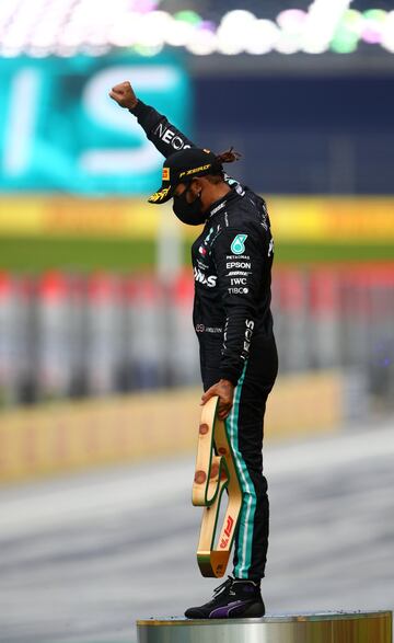 Lewis Hamilton celebra la victoria con el puño en alto y trofeo en mano. 