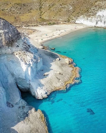 La Cala de Enmedia resulta ser uno de los mejores enclaves de Almería. Un pequeño rincón de la costa del Cabo de Gata. Está rodeada de dunas plateadas fosilizadas por las que caminar y disfrutar explorando pequeñas pozas inundadas. Sus aguas turquesas y cristalinas son perfectas para hacer snorkel, además de tener unas vistas inmejorables a la Mesa Roldán y su castillo.