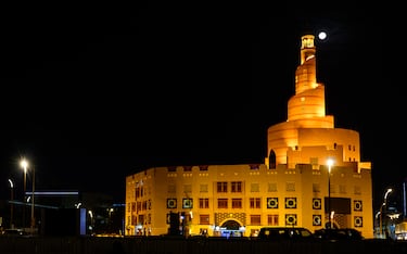La Luna brilla sobre minarete iluminado de la mezquita Al Fanar en Doha, Catar.