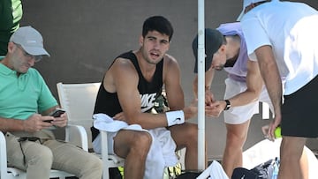 Carlos Alcaraz, atendido por su fisio y preparador, Juanjo Moreno.