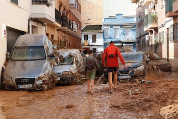 La gente camina por una calle cubierta de barro tras las lluvias torrenciales que provocaron inundaciones, en Paiporta, Valencia.