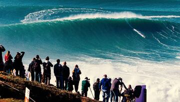 Gente mirando desde el acantilado el espectáculo del surf en las olas gigantes de Nazaré (Portugal).