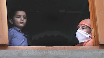 Srinagar (India), 20/06/2020.- Relatives look out of a window of a funeral house during the funeral of a victim, who died with COVID-19 in Srinagar, the summer capital of Indian Kashmir, India, 20 June 2020. The Indian government has eased some coronaviru